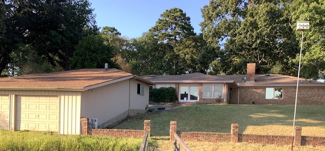 back of property featuring a garage and a lawn