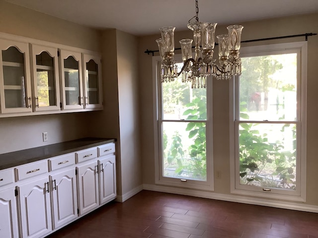 unfurnished dining area with dark hardwood / wood-style floors and an inviting chandelier