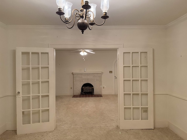 unfurnished living room with carpet, ornamental molding, ceiling fan with notable chandelier, and a brick fireplace