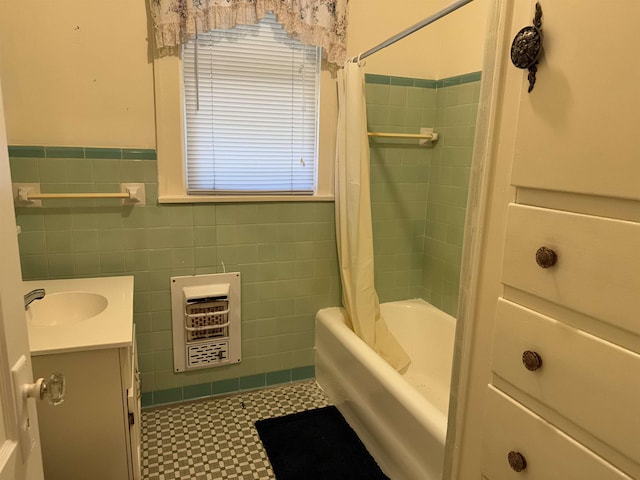 bathroom featuring heating unit, shower / bath combo with shower curtain, vanity, and tile walls