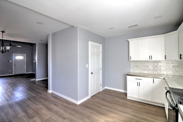 kitchen with white cabinetry, dark wood-type flooring, and backsplash