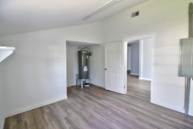 unfurnished room featuring vaulted ceiling, light hardwood / wood-style floors, and electric water heater