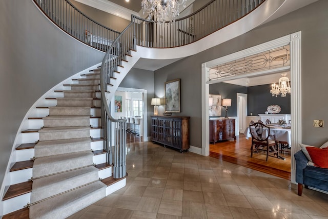 stairway featuring dark tile floors, crown molding, a chandelier, and a high ceiling