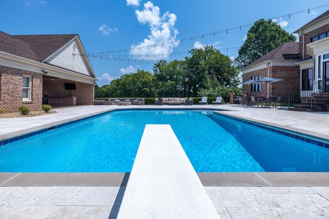 view of pool with a diving board and a patio area