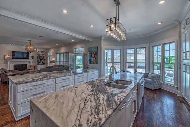 kitchen with sink, an island with sink, a healthy amount of sunlight, and white cabinets