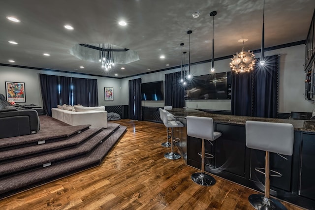 interior space with a kitchen bar, hanging light fixtures, a notable chandelier, and hardwood / wood-style flooring