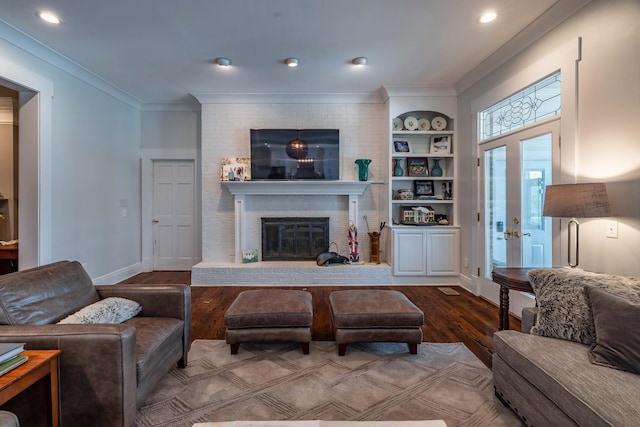 living room featuring a brick fireplace, built in shelves, french doors, dark hardwood / wood-style flooring, and ornamental molding