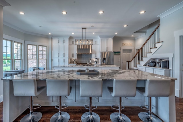 kitchen with a kitchen island, hanging light fixtures, stainless steel fridge, and white cabinetry