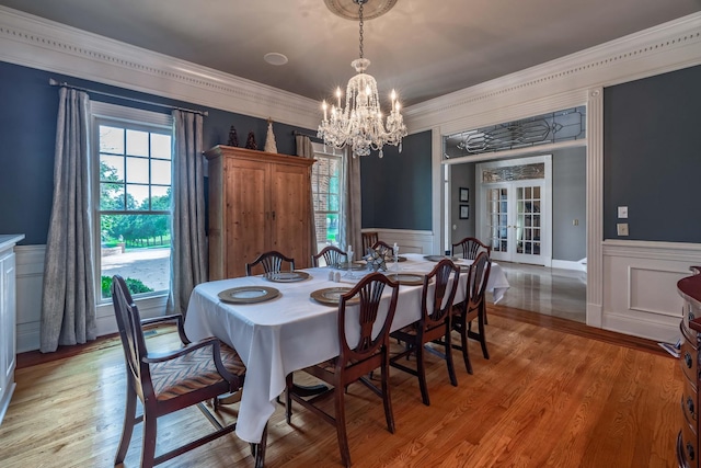 dining space with crown molding, french doors, a chandelier, and light wood-type flooring