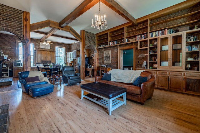 living room with light hardwood / wood-style flooring, brick wall, beamed ceiling, and ceiling fan with notable chandelier