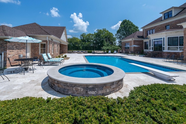 view of swimming pool with an outdoor hot tub, a diving board, and a patio area