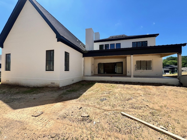 rear view of house featuring crawl space, a patio area, and a chimney