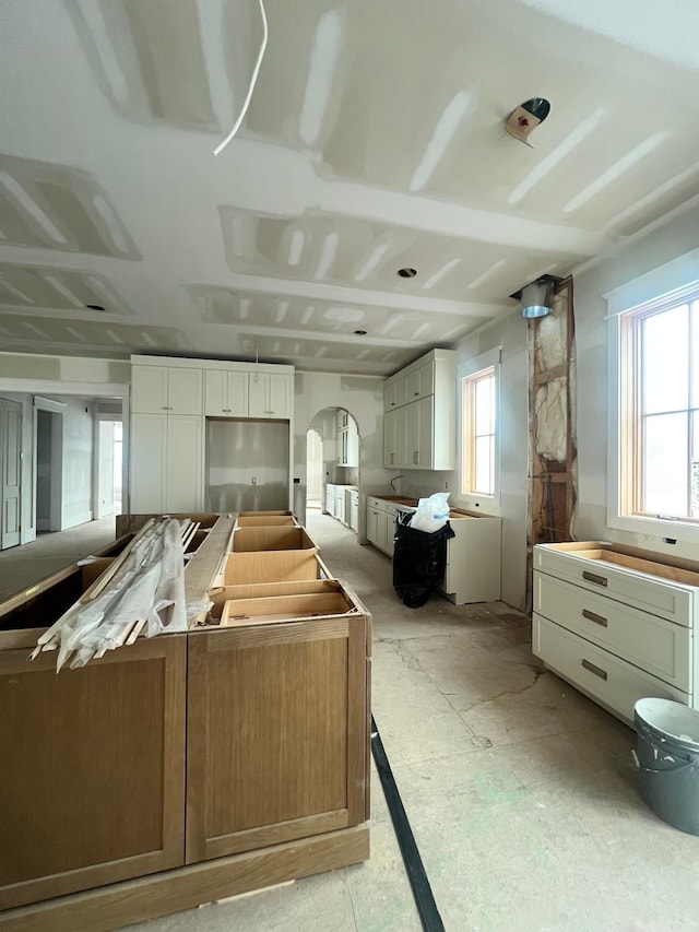 interior space featuring arched walkways, a center island, and white cabinets