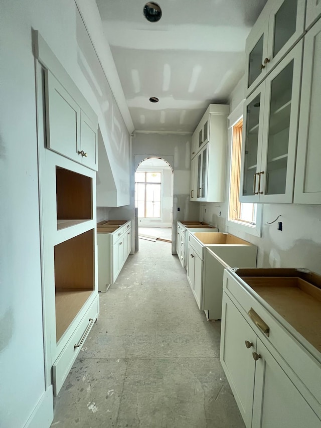 kitchen with glass insert cabinets, arched walkways, and white cabinets