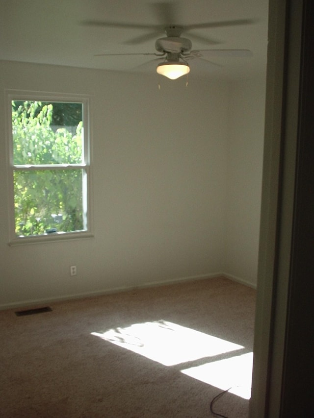 empty room with carpet flooring, a healthy amount of sunlight, and ceiling fan