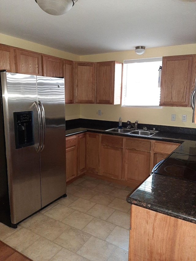 kitchen with dark stone countertops, high end fridge, sink, and light tile flooring