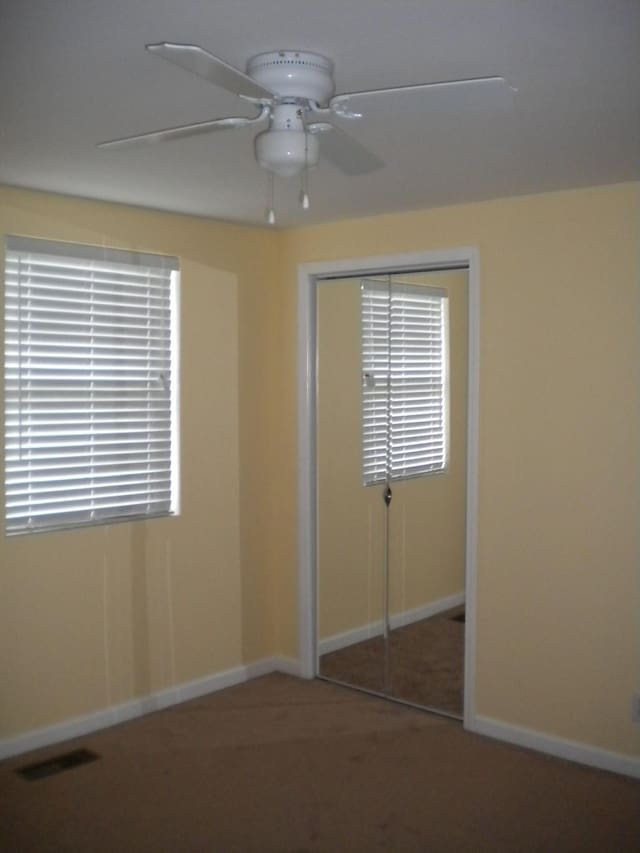 unfurnished bedroom featuring a closet, ceiling fan, and dark colored carpet