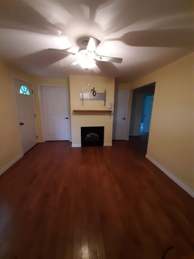 unfurnished living room with dark hardwood / wood-style flooring and ceiling fan