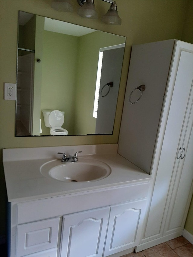 bathroom with tile flooring, toilet, and vanity