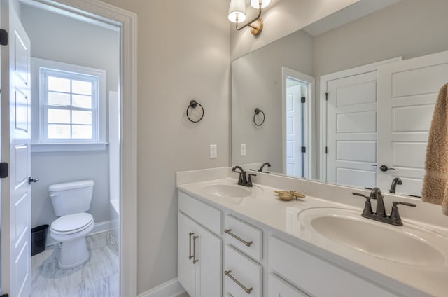 bathroom with dual sinks, toilet, tile flooring, and vanity with extensive cabinet space