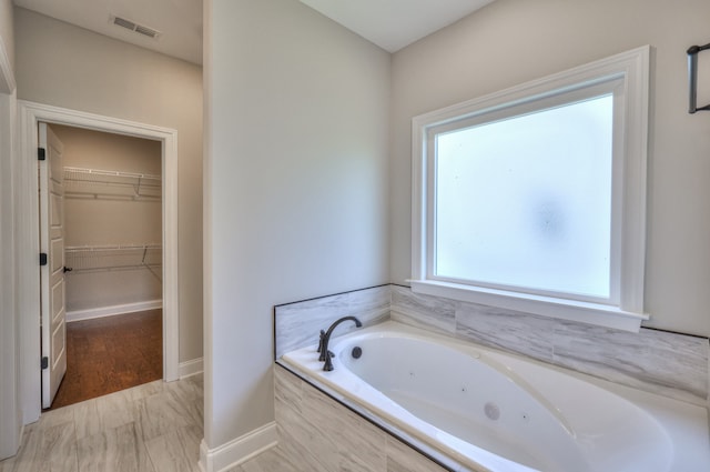 bathroom with wood-type flooring and tiled bath