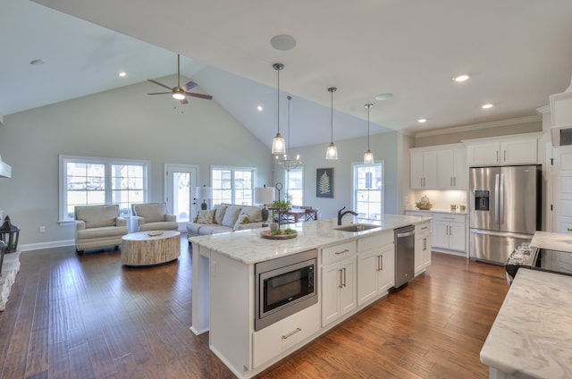 kitchen featuring a kitchen island with sink, white cabinets, light stone countertops, dark wood-type flooring, and stainless steel appliances