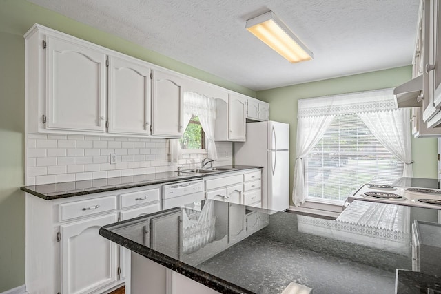 kitchen with white appliances, white cabinets, backsplash, and wall chimney exhaust hood