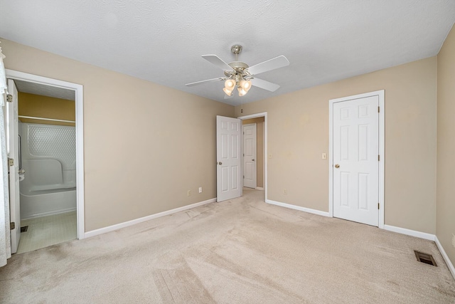 unfurnished bedroom with light carpet, connected bathroom, a textured ceiling, and ceiling fan