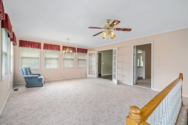 unfurnished room featuring light carpet, ornamental molding, french doors, and ceiling fan with notable chandelier