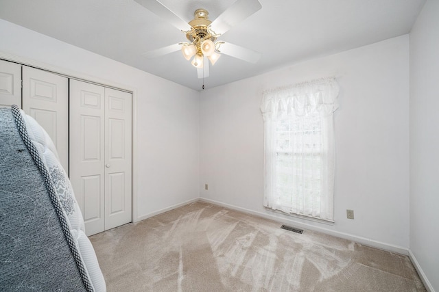 unfurnished bedroom with ceiling fan, a closet, and light carpet