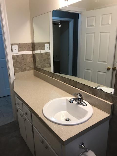 bathroom with backsplash, vanity with extensive cabinet space, and tile flooring