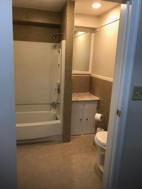 full bathroom with shower / washtub combination, vanity, tile walls, tile flooring, and toilet