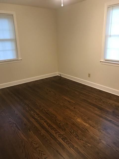 empty room featuring a healthy amount of sunlight and dark hardwood / wood-style flooring