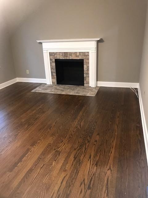 unfurnished living room with a fireplace and dark wood-type flooring