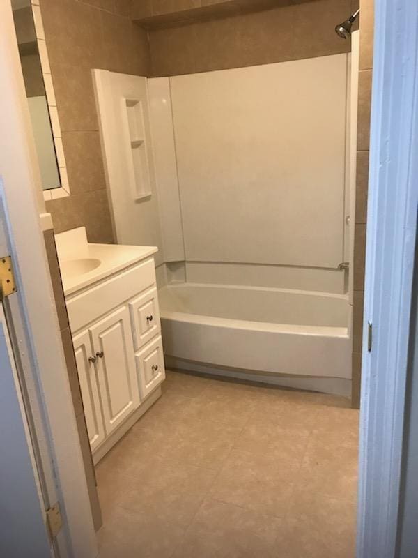 bathroom with tile flooring, bathtub / shower combination, vanity, and tile walls