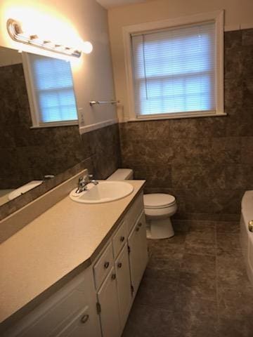 bathroom featuring a healthy amount of sunlight, toilet, tile floors, and large vanity