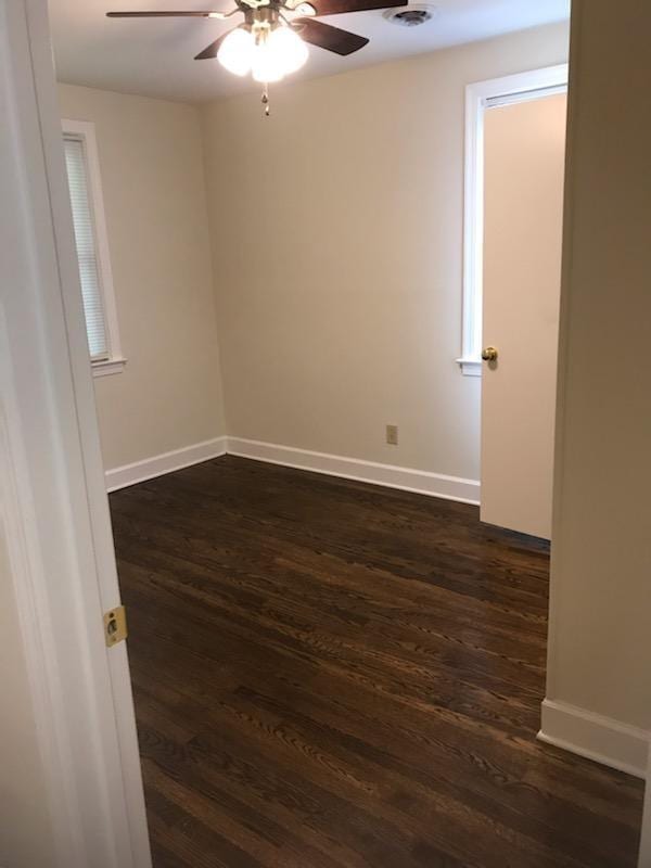 empty room with dark wood-type flooring and ceiling fan