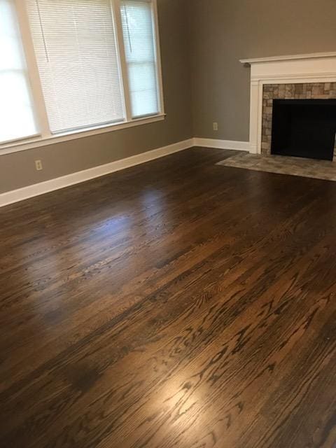 unfurnished living room featuring a wealth of natural light, dark wood-type flooring, and a fireplace