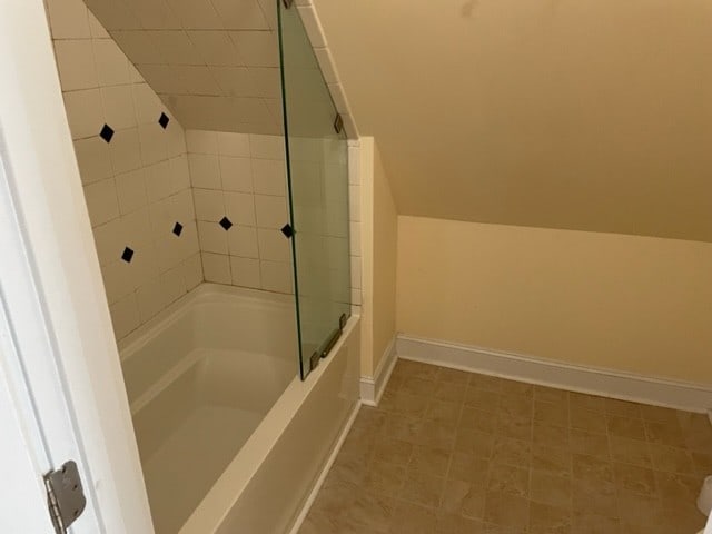 bathroom with tile flooring and shower / bath combination with glass door