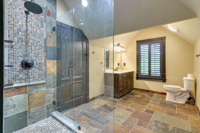 bathroom with lofted ceiling, toilet, vanity, and a shower with shower door