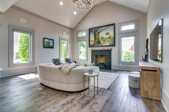 living room featuring an inviting chandelier, plenty of natural light, a high end fireplace, and wood-type flooring