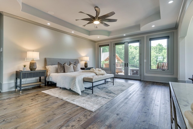 bedroom featuring french doors, dark wood-type flooring, a tray ceiling, and multiple windows