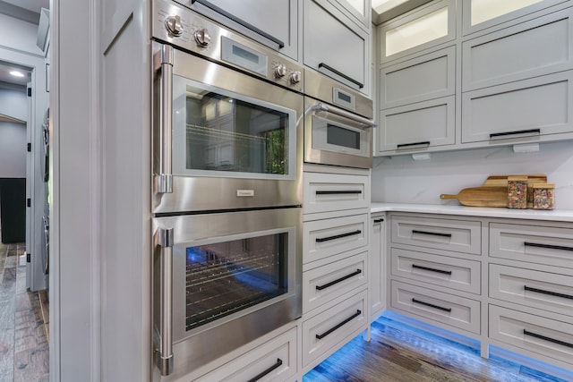 kitchen with dark hardwood / wood-style flooring and stainless steel double oven