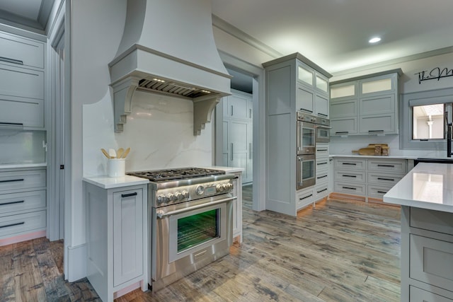 kitchen with custom range hood, hardwood / wood-style floors, and stainless steel appliances