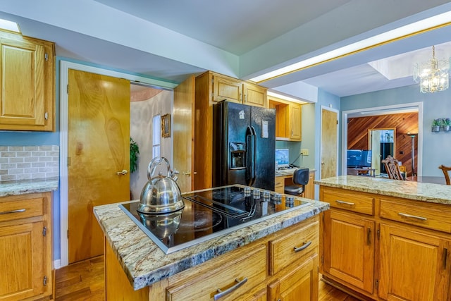 kitchen featuring decorative backsplash, black appliances, light hardwood / wood-style flooring, a chandelier, and a center island