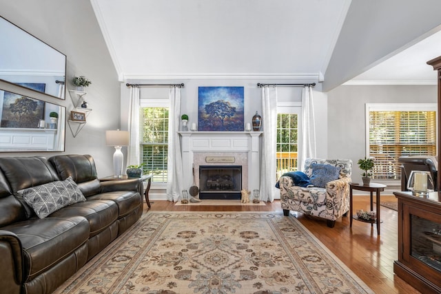 living room featuring lofted ceiling, a high end fireplace, ornamental molding, and hardwood / wood-style floors