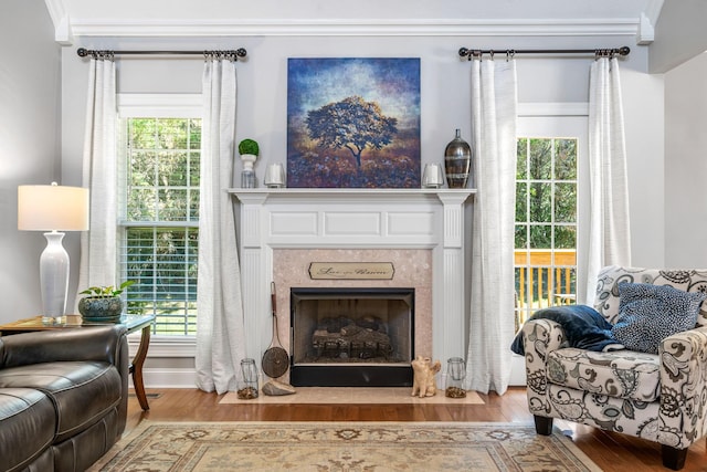 sitting room with plenty of natural light, crown molding, and light wood-type flooring