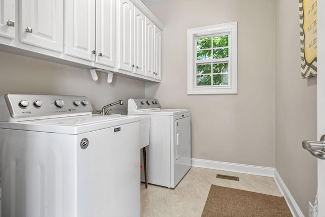 clothes washing area featuring light tile floors, cabinets, and washing machine and dryer