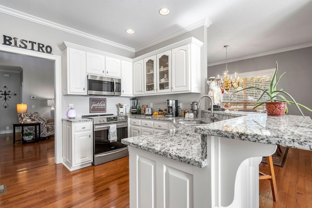 kitchen with dark hardwood / wood-style flooring, a chandelier, white cabinetry, stainless steel appliances, and hanging light fixtures