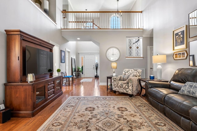 living room featuring a towering ceiling, an inviting chandelier, and light hardwood / wood-style floors